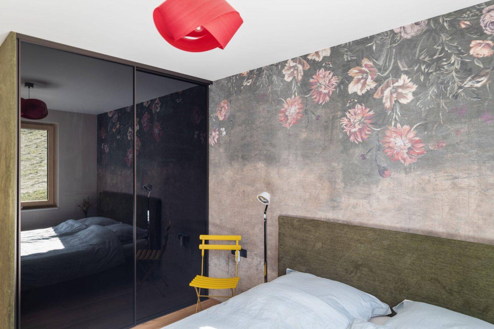 Gemütliches Schlafzimmer mit floraler Tapete und elegantem Spiegelschrank.
