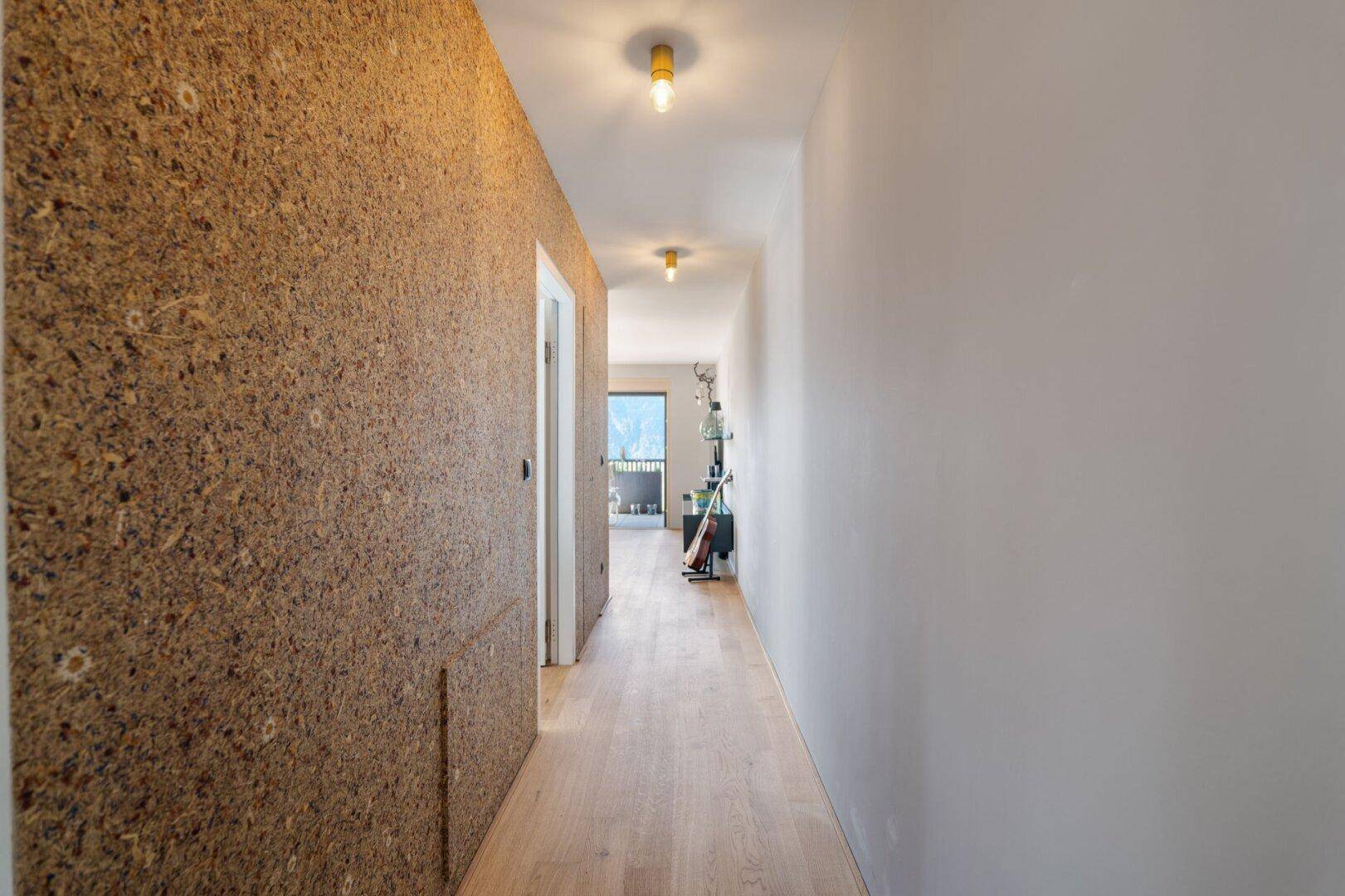 Heller Flur mit Holzboden und einer strukturierten Wandverkleidung.