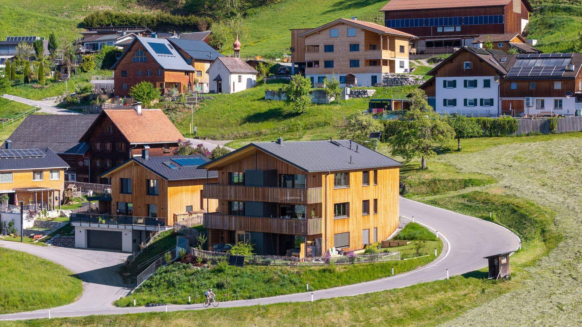 Moderne Wohngebäude in ländlicher Umgebung mit grünen Wiesen und Bergblick.