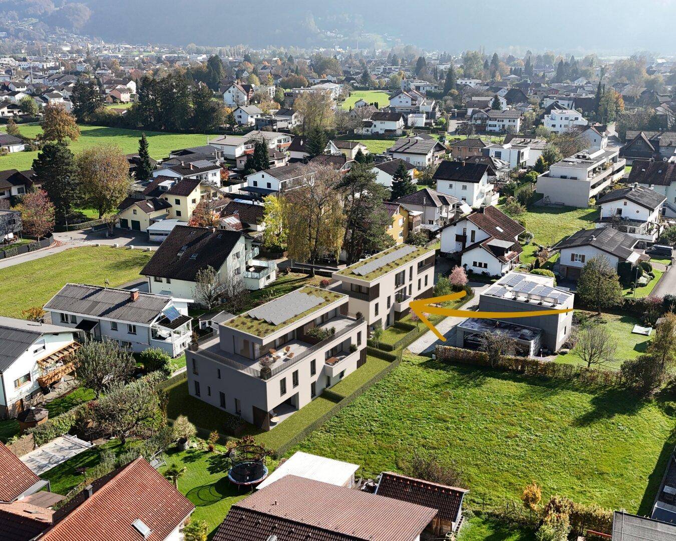Luftaufnahme einer geplanten Wohnanlage mit Gründächern, eingebettet in eine bestehende Wohnsiedlung.