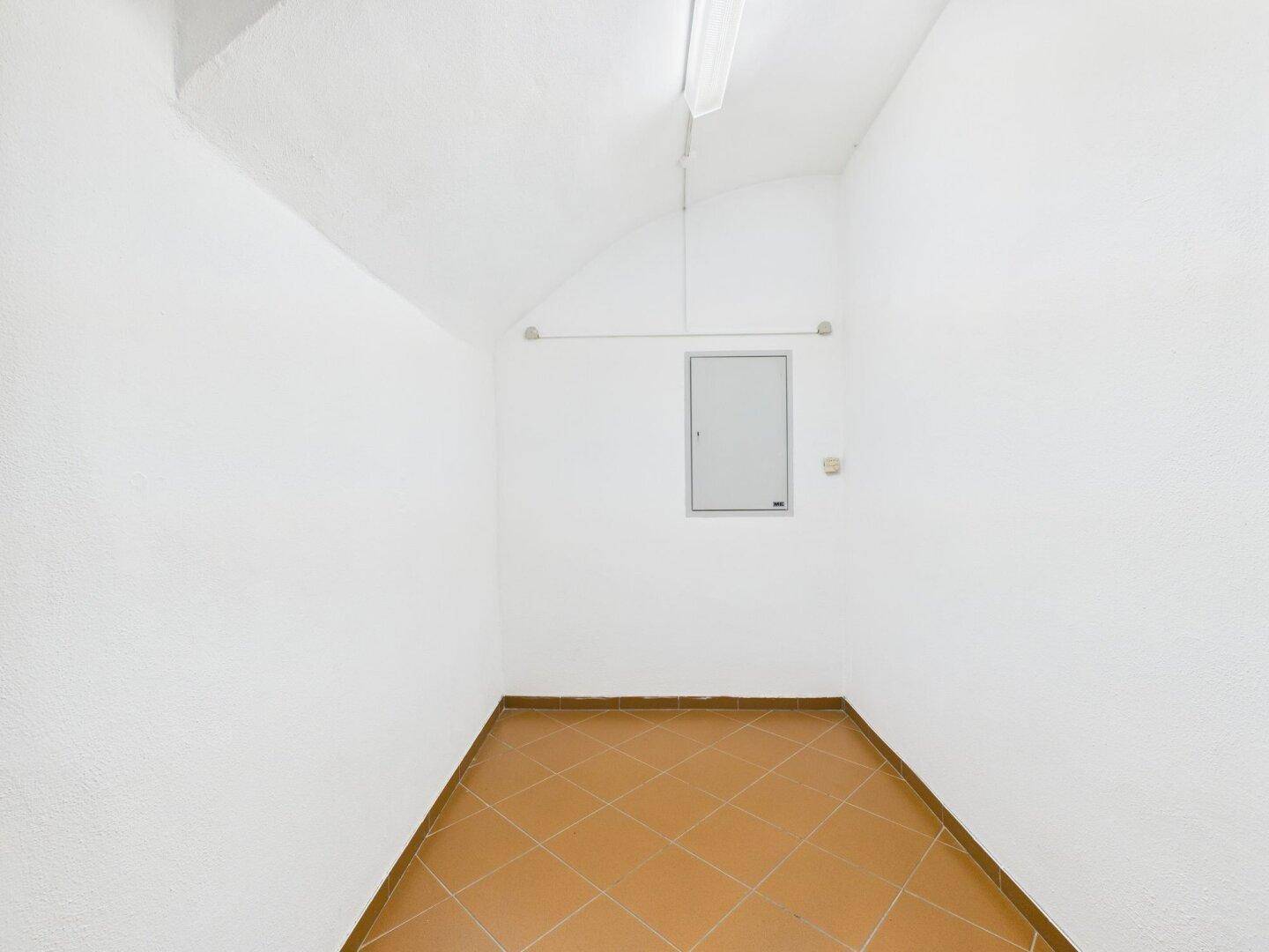 Leerer Abstellraum mit gewölbter Decke, Terrakottafliesen und einem Sicherungskasten an der Wand.