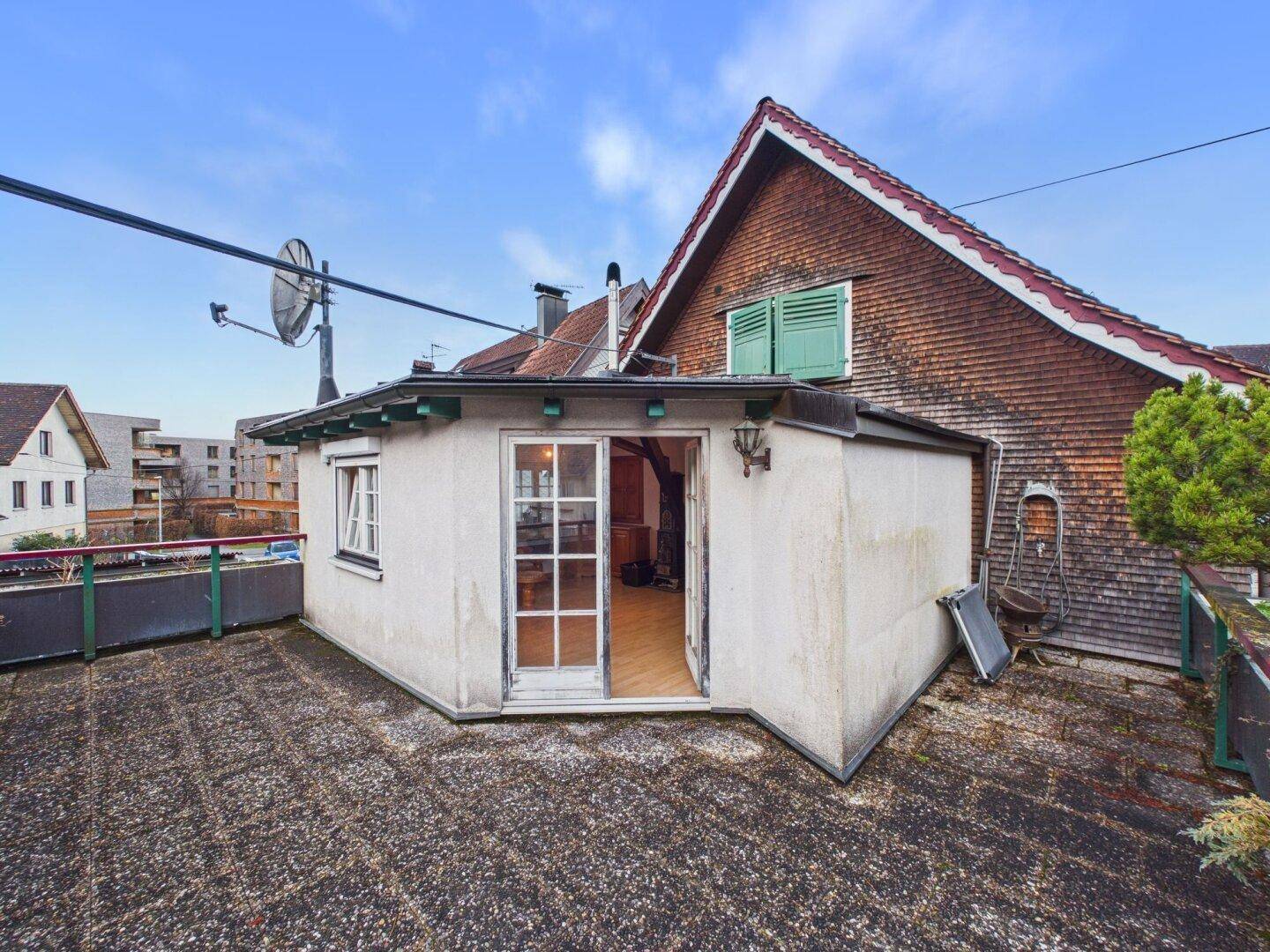 Dachterrasse mit kleinem Anbau und Blick auf die umliegenden Dächer.
