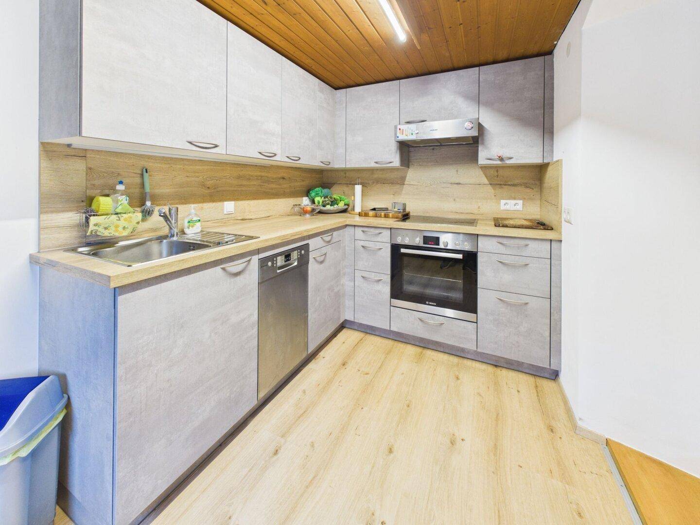Moderne Einbauküche mit grauen Fronten, Holzarbeitsplatte und Dachschrägen.