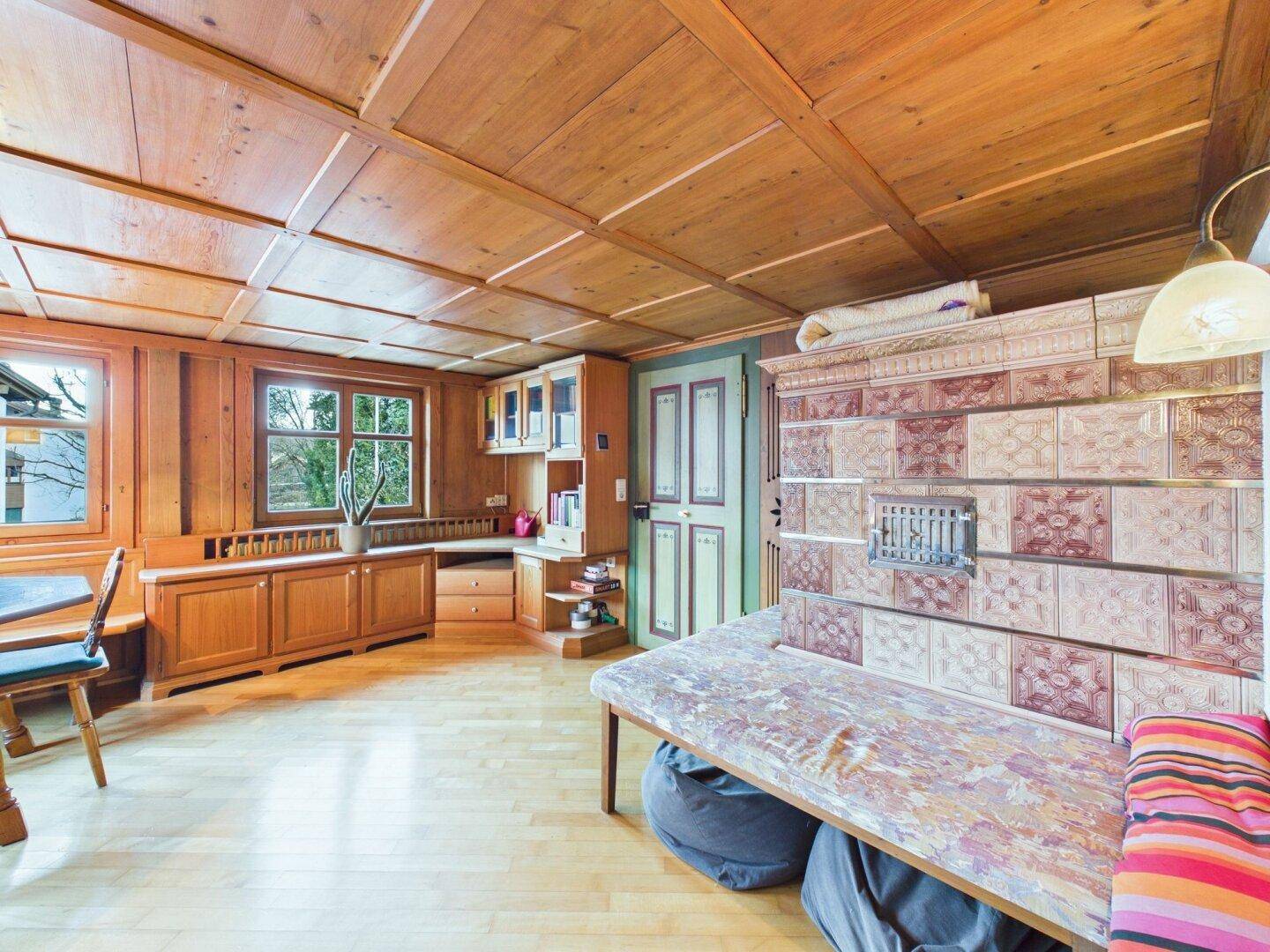 Traditionelles Wohnzimmer mit Holztäfelung, Kassettendecke und einem Kachelofen.