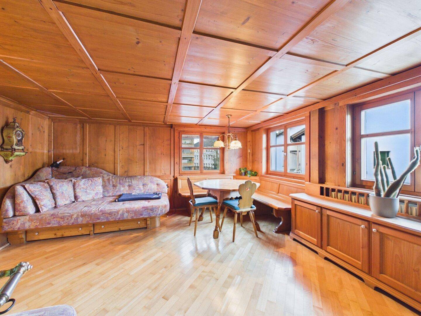 Rustikales Wohnzimmer mit Holztäfelung, Kassettendecke und traditionellen Möbeln.