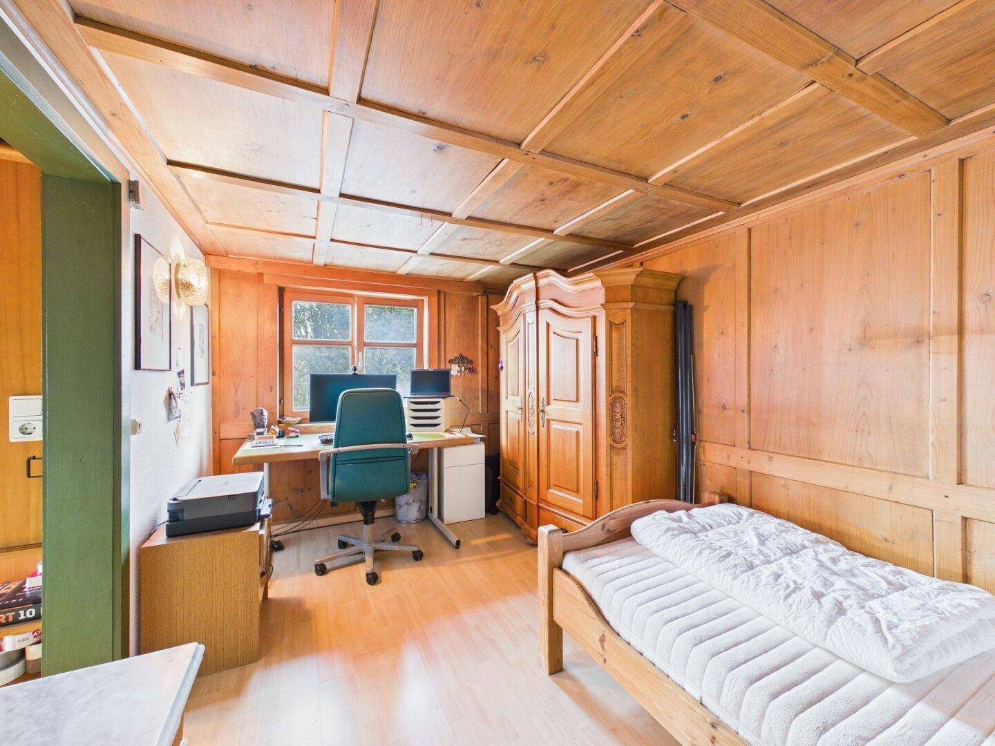 Arbeitszimmer mit Holztäfelung, Kassettendecke und einem Einzelbett.