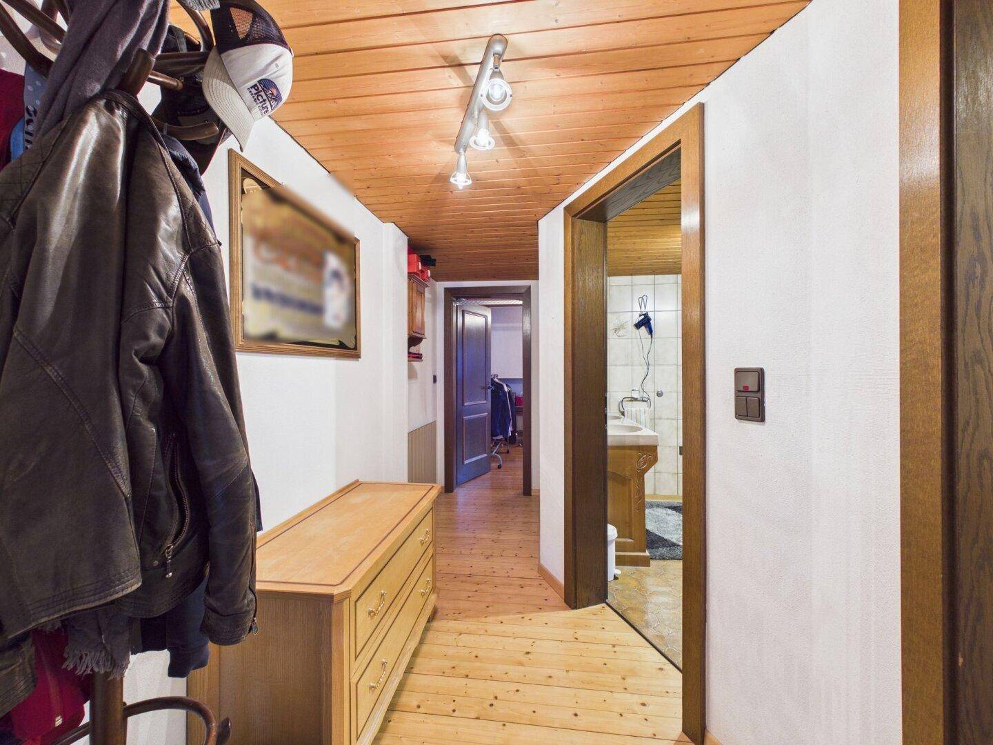 Heller Flur mit Holzfußboden, Garderobe und Zugang zu weiteren Räumen.