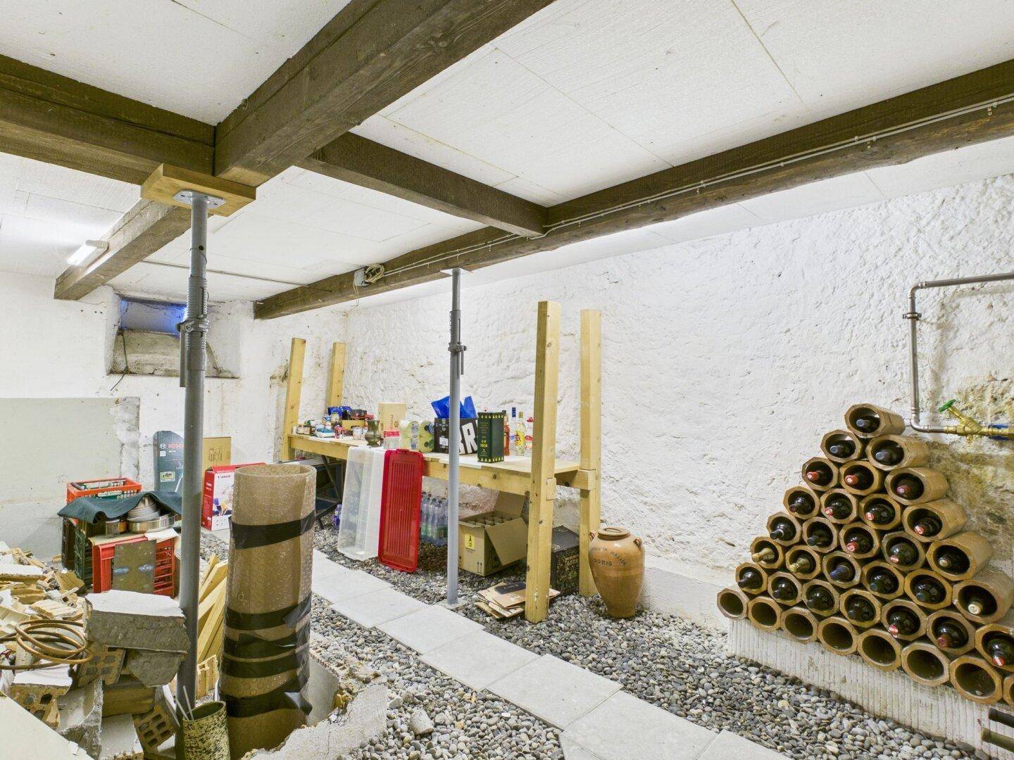 Geräumiger Kellerraum mit sichtbaren Holzbalken und praktischer Weinlagerung.