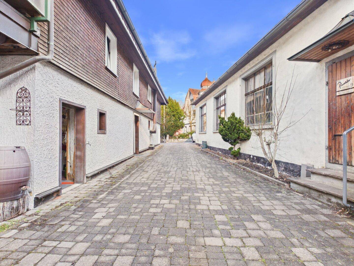 Schmale gepflasterte Gasse zwischen historischen Gebäuden mit traditioneller Architektur.