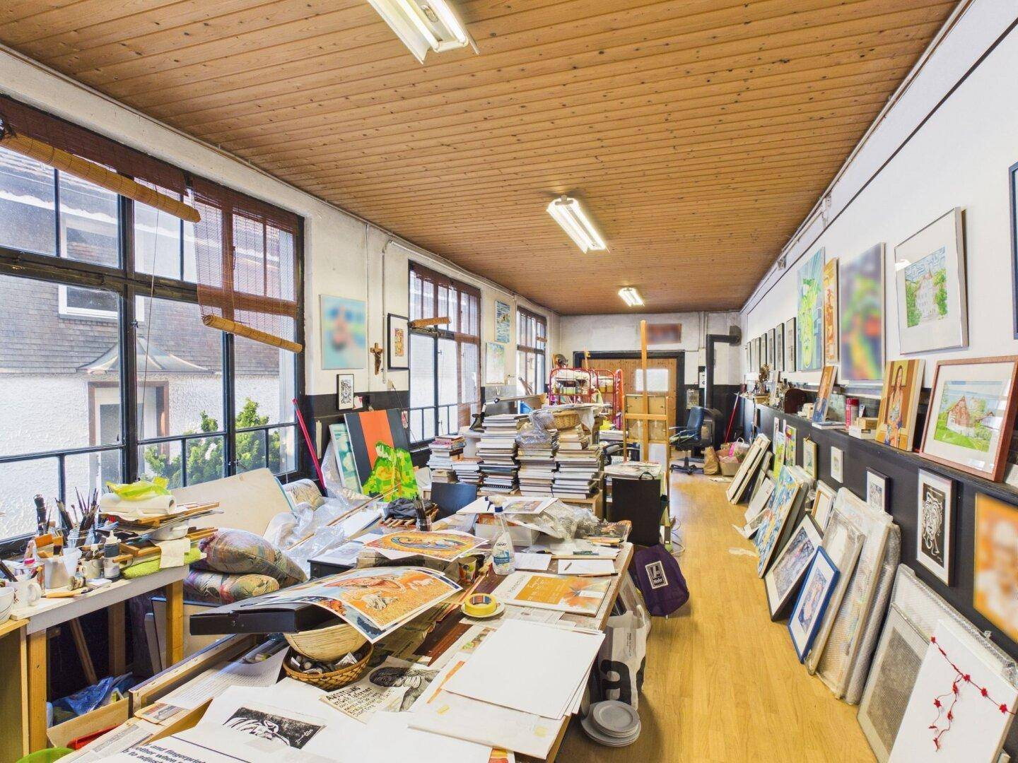 Helles Atelier oder Büro mit vielen Fenstern, Holzdecke und kreativer Arbeitsatmosphäre.