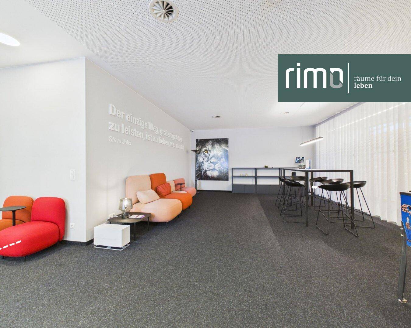 Gemütlicher Loungebereich in einem Büro mit bequemen Sofas, Stehtischen und inspirierender Wandgestaltung.