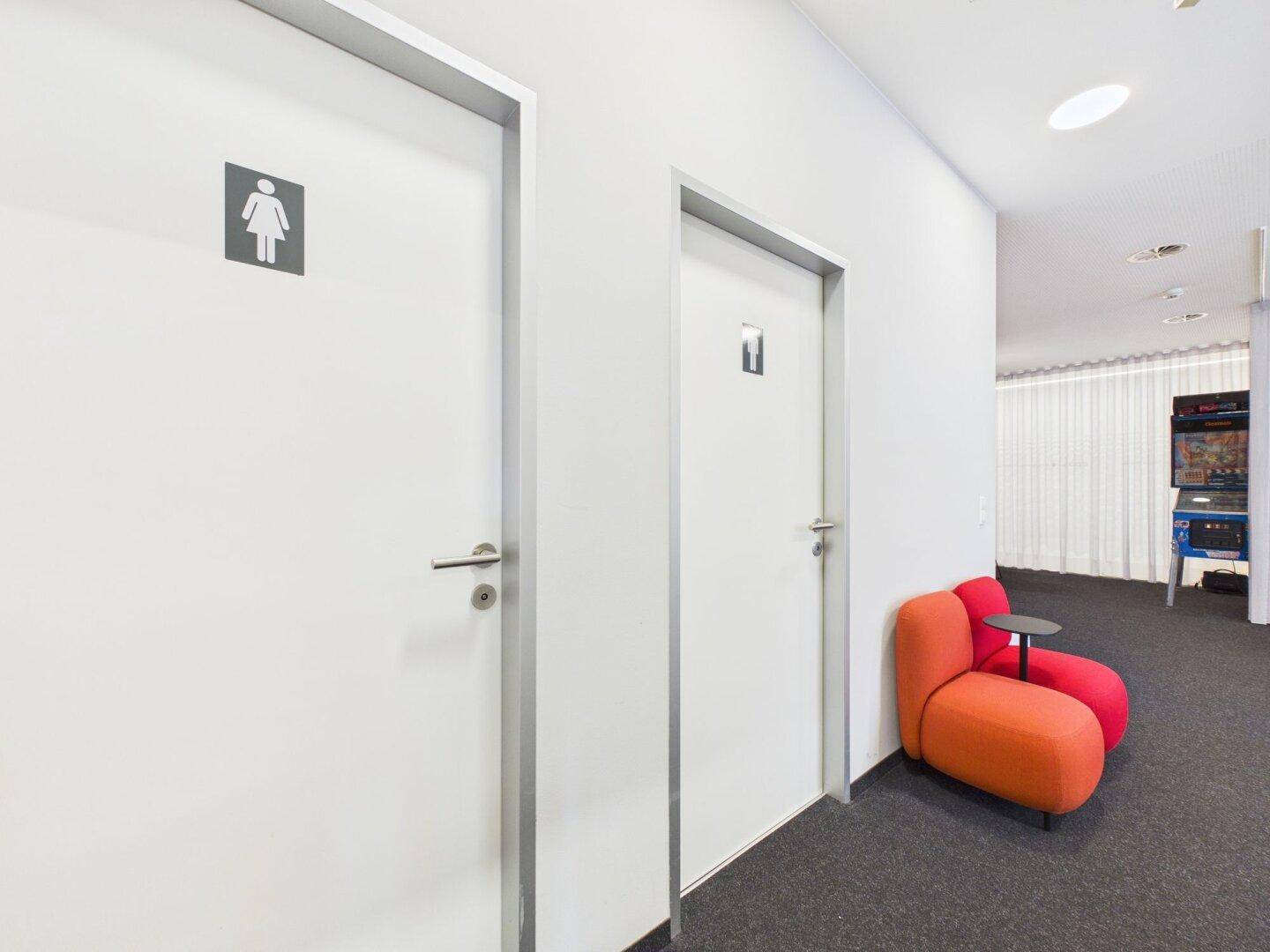 Zwei Türen zu den Toilettenbereichen, sichtbar vom Loungebereich des Büros aus.