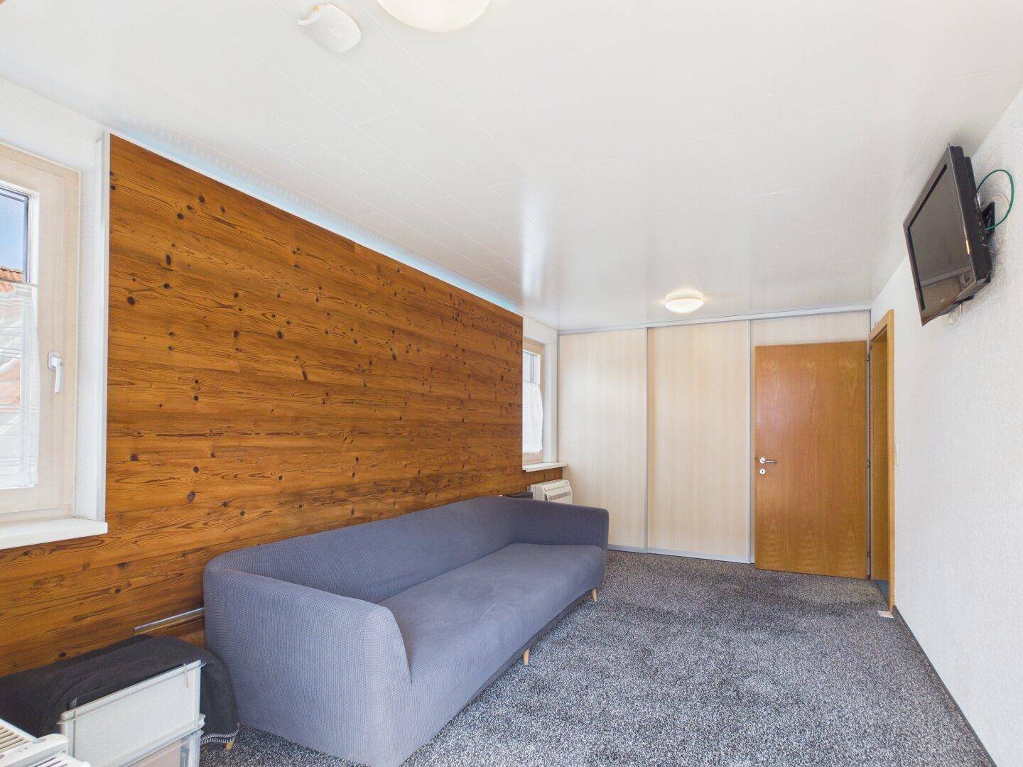 Schlafzimmer mit Holzwand, Teppichboden und Einbauschränken.