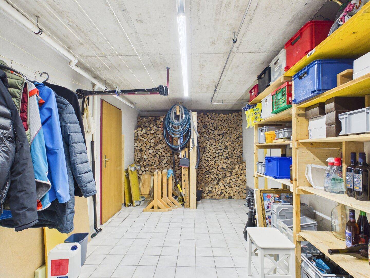 Abstellraum mit Holzstapel für den Kaminofen und weiteren Lagerflächen.