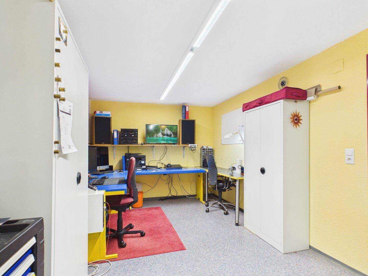 Helles Büro mit mehreren Arbeitsplätzen, Computern und gelben Wänden.