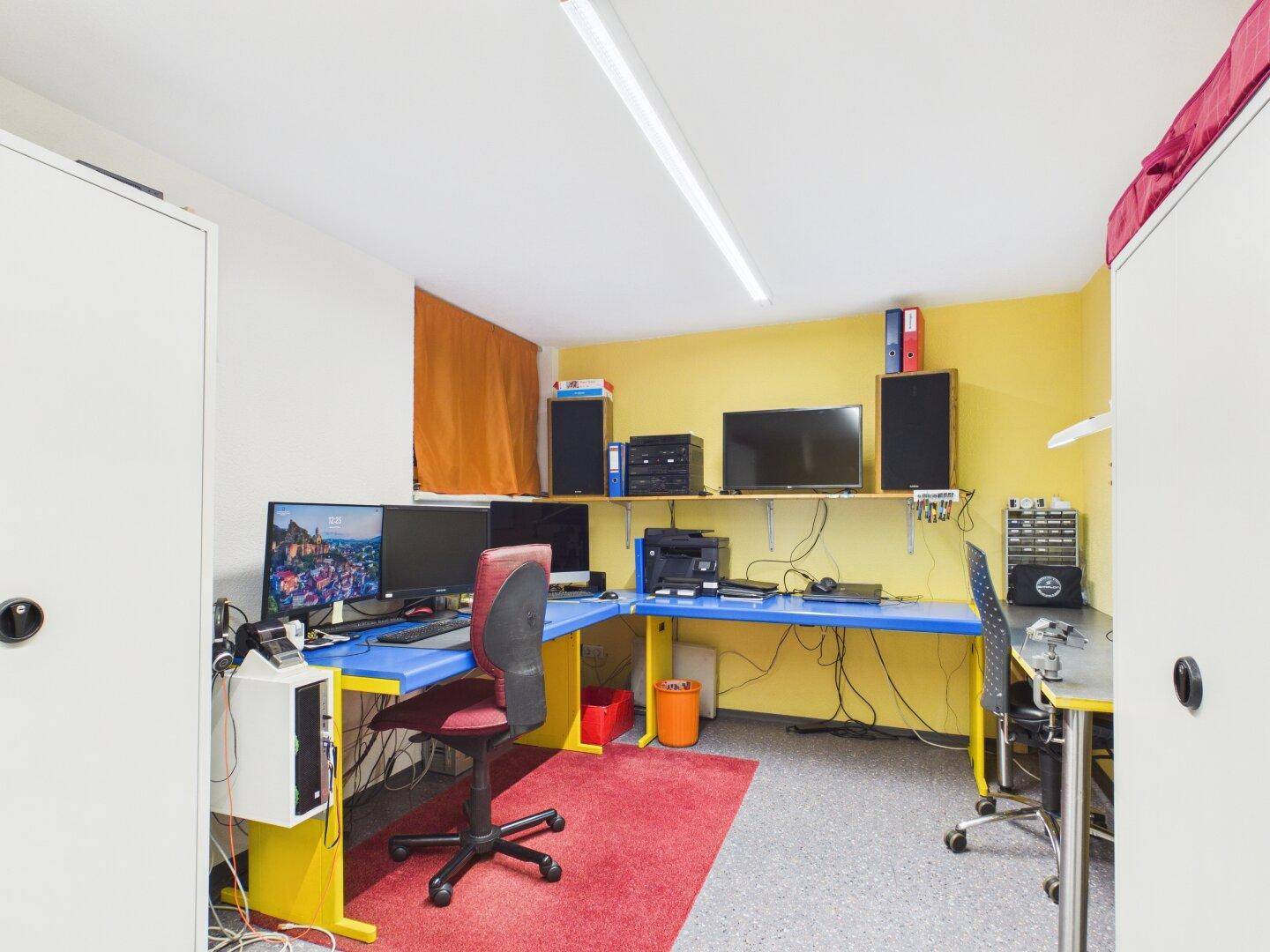 Büro mit Computern, Schreibtischen und gelben Wänden für kreatives Arbeiten.
