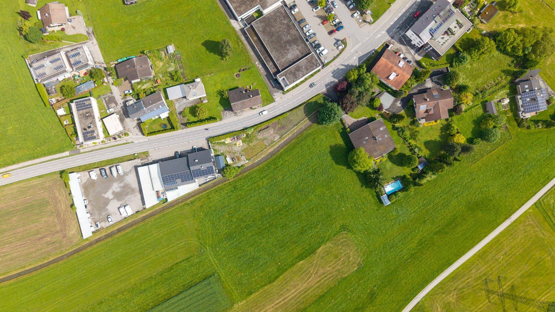 Luftaufnahme einer ländlichen Siedlung mit Häusern, Feldern und einer Straße.