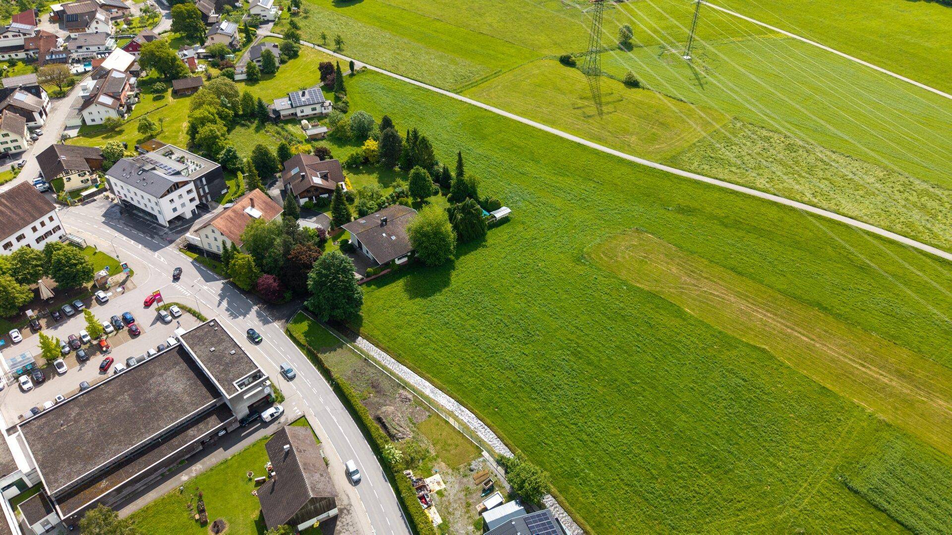 Luftaufnahme einer ländlichen Gegend mit Feldern, Häusern und einer kurvigen Straße.