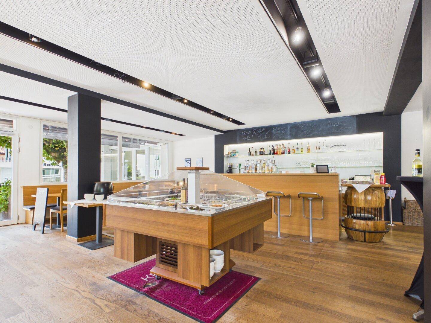 Moderner Restaurantbereich mit einer Salatbar, einer gut ausgestatteten Bar und Holzböden.