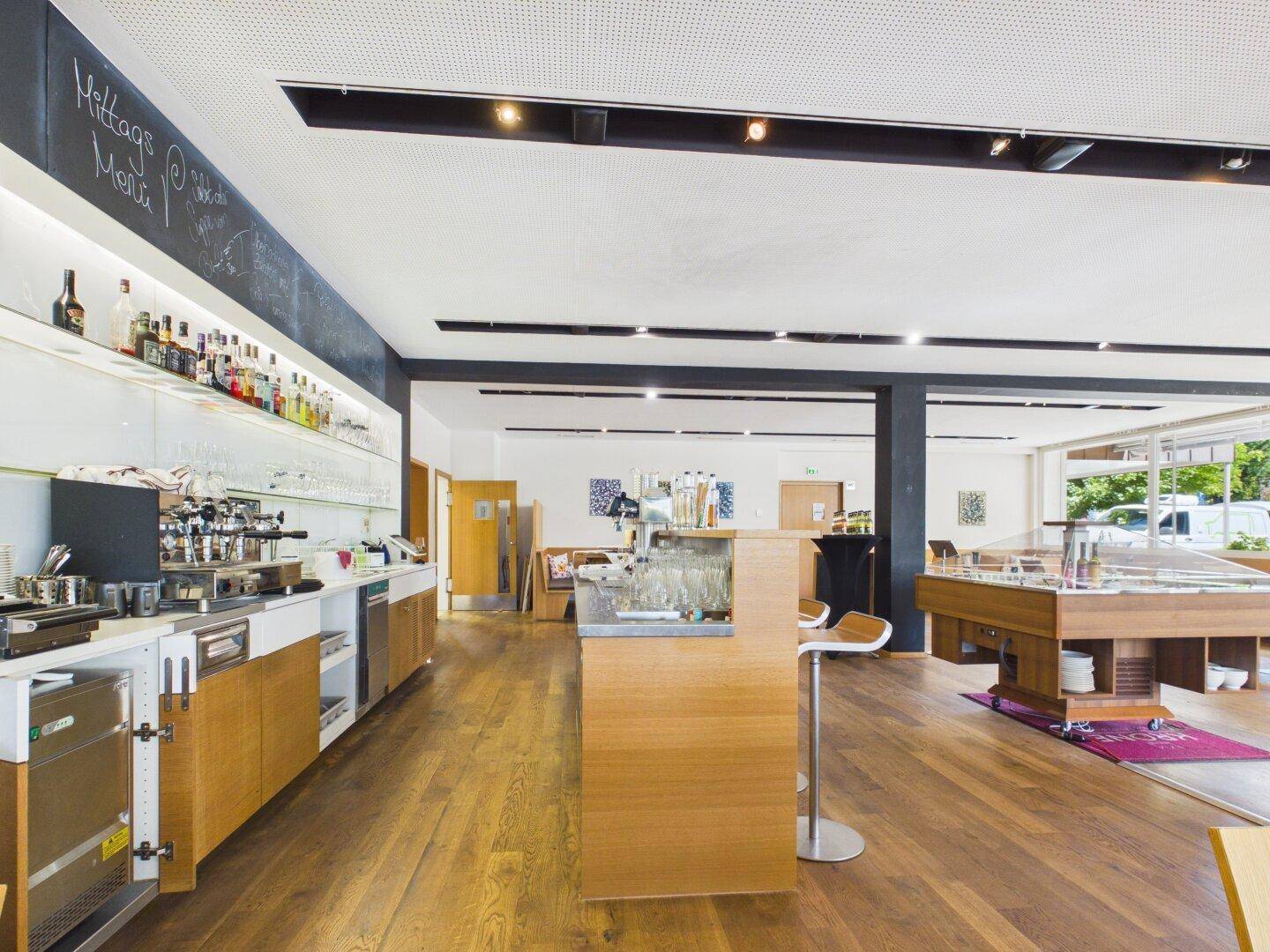 Gut ausgestatteter Barbereich mit Kaffeemaschinen, Kühlschränken und einer langen Theke in einem modernen Ambiente.