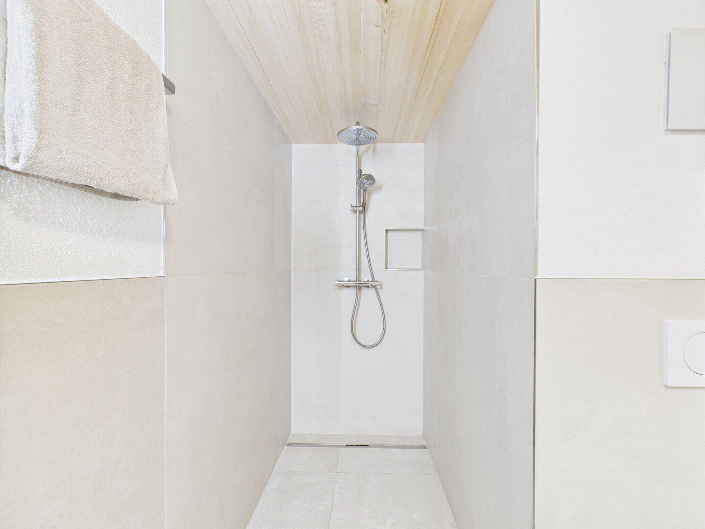 Geräumige begehbare Dusche mit Regenduschkopf und modernen Fliesen.