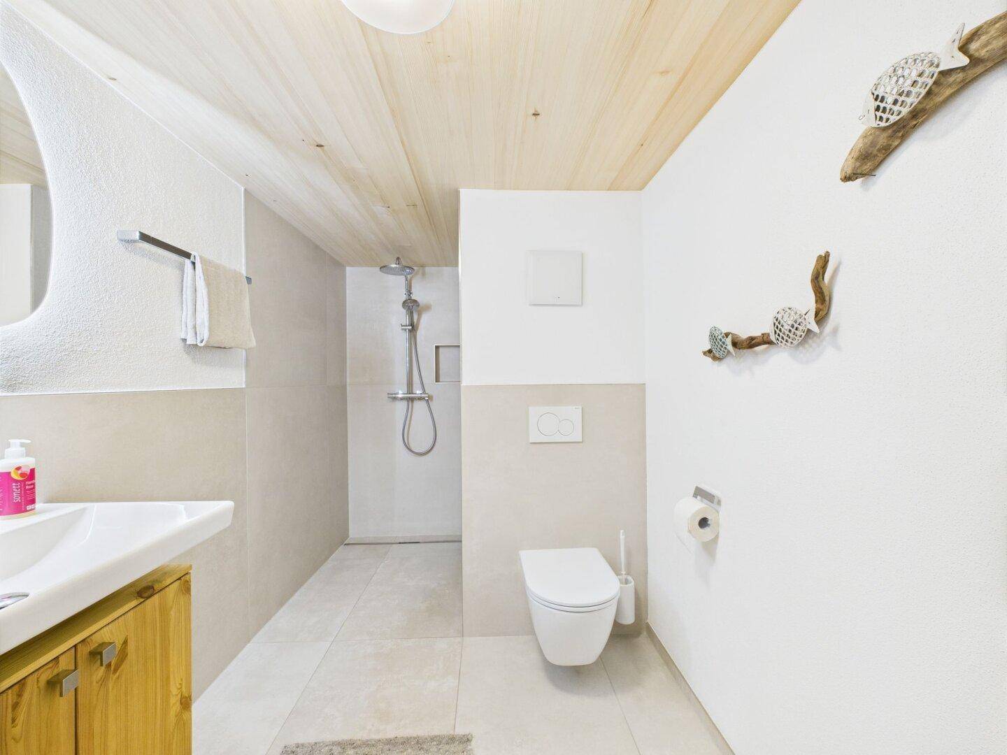 Modernes Badezimmer mit Dusche, wandhängendem WC und Waschbecken.