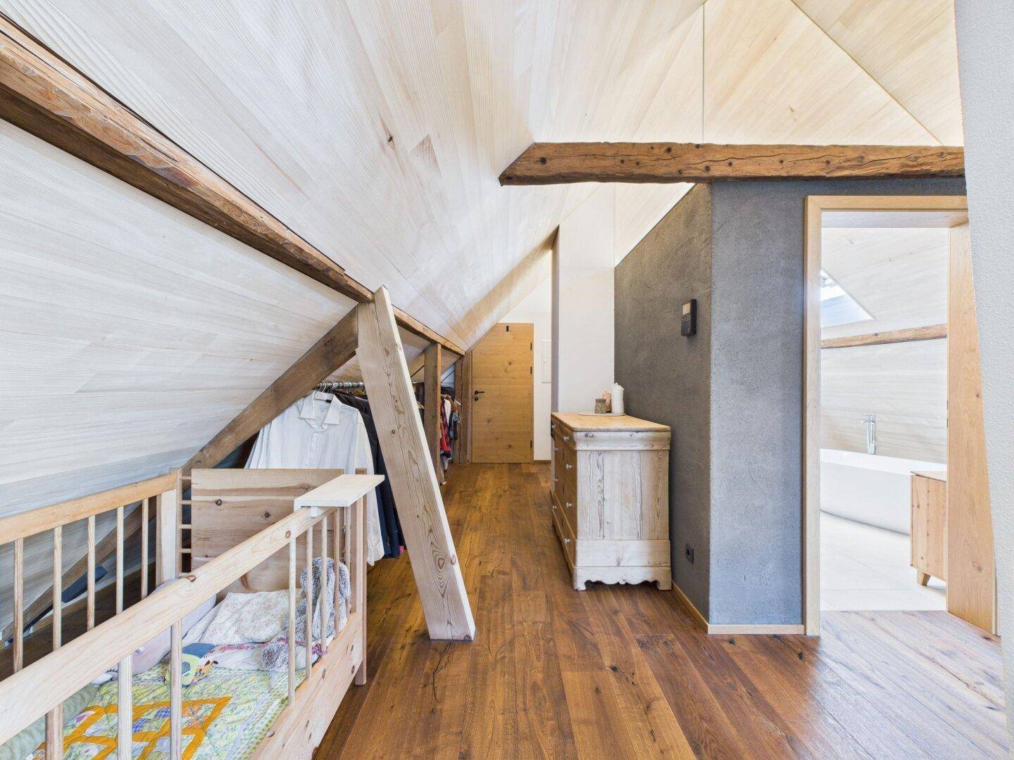 Flur im Dachgeschoss mit Holzboden, Dachschräge und Zugang zu einem modernen Badezimmer.