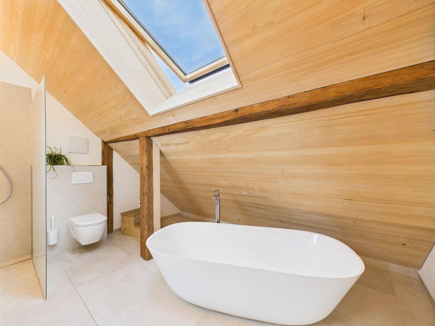 Modernes Badezimmer im Dachgeschoss mit freistehender Badewanne, Dusche und Dachfenster.