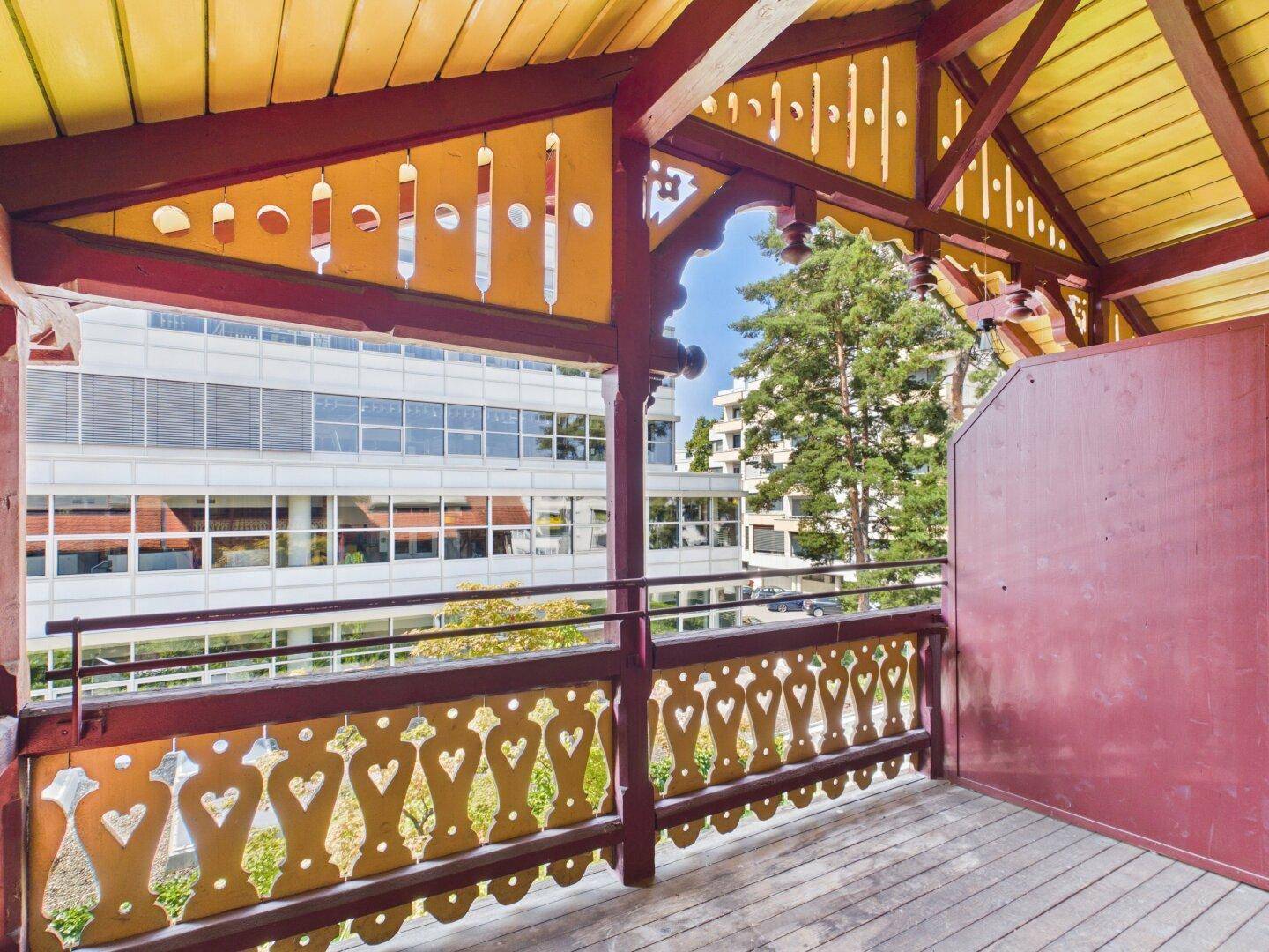 Geräumiger Holzbalkon mit traditionellen Verzierungen und Blick auf die Umgebung.