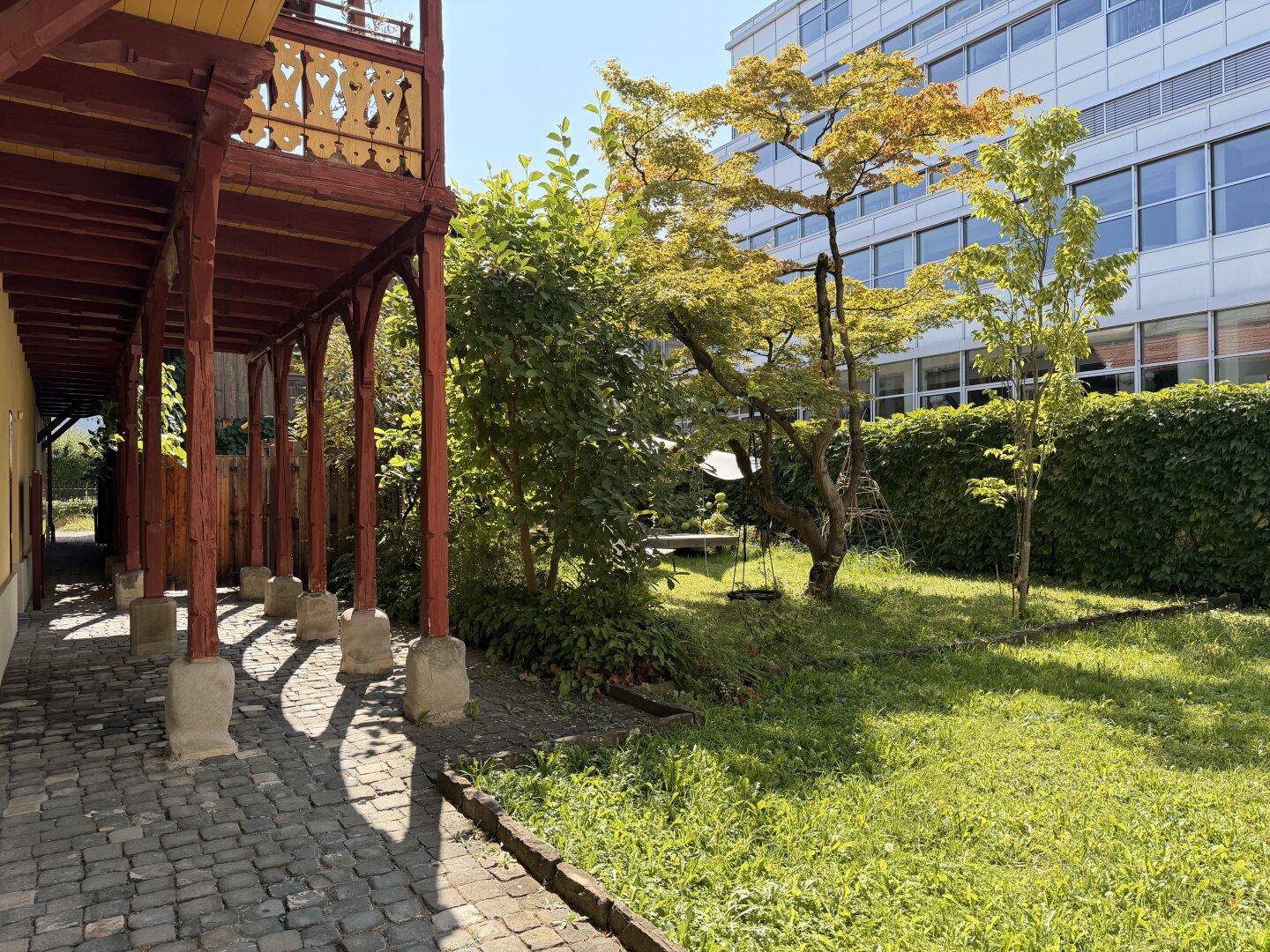 Gartenweg mit Kopfsteinpflaster und Blick auf das historische Gebäude und moderne Umgebung.