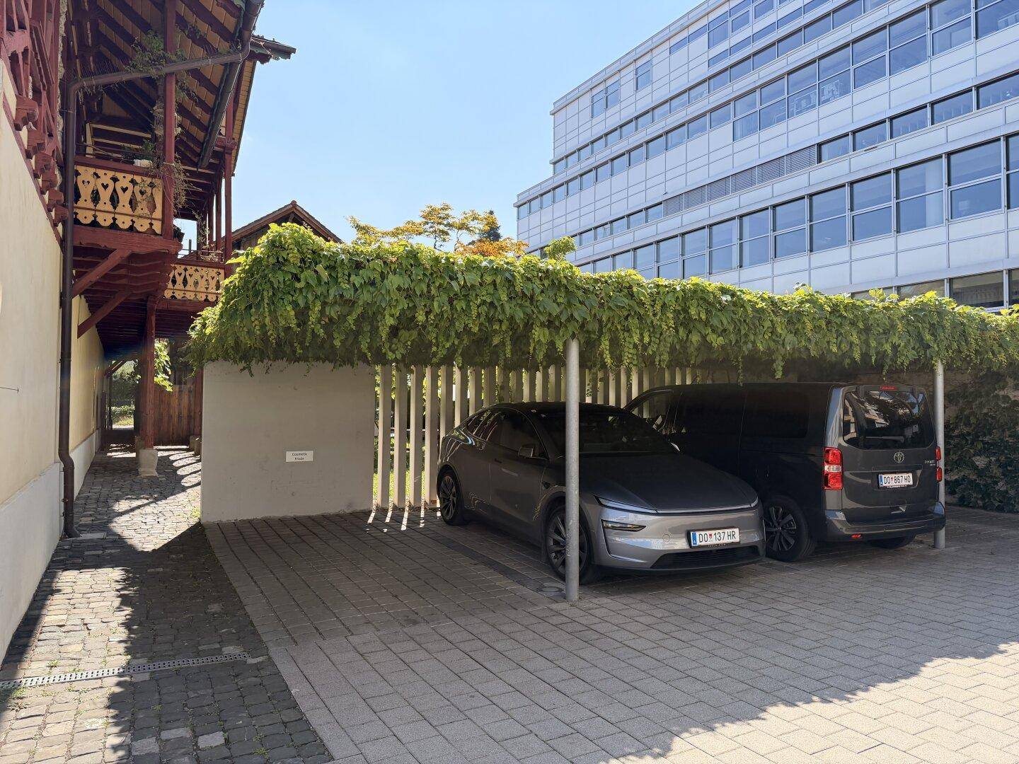 Überdachter Parkplatz mit zwei Fahrzeugen und begrüntem Dach.