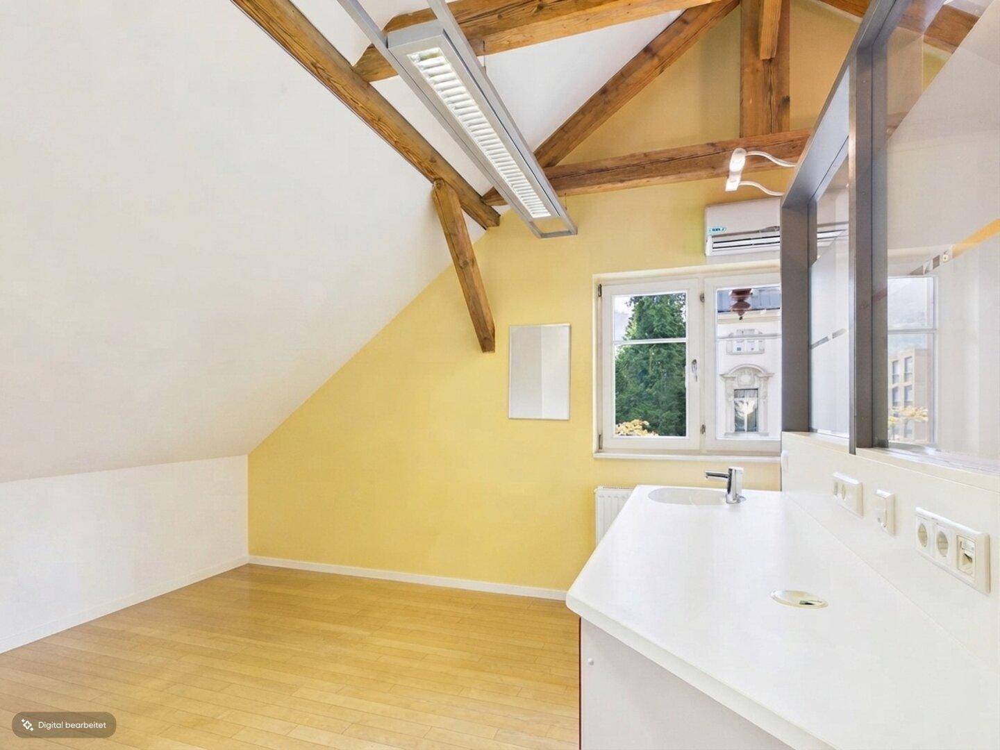 Gelb gestrichener Büroraum mit Holzbalken, Fenster und Klimaanlage.