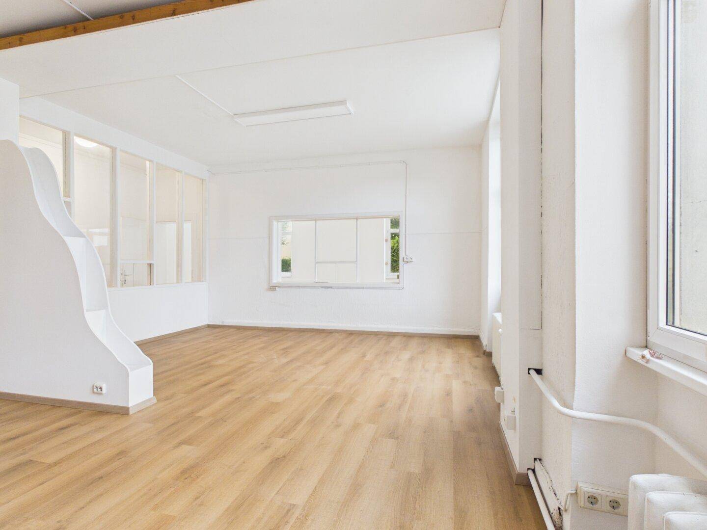 Heller, leerer Raum mit modernem Holzboden und weißen Wänden, bereit zur individuellen Gestaltung.