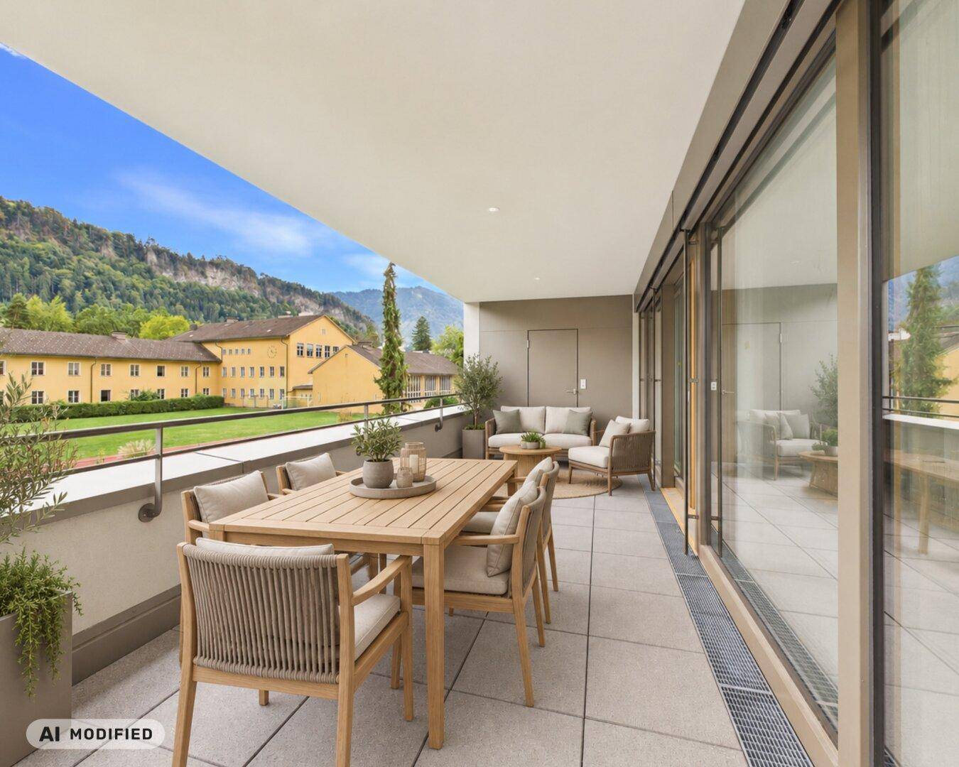 Großer, möblierter Balkon mit Ess- und Lounge-Bereich, bietet einen weiten Blick auf die Berge.