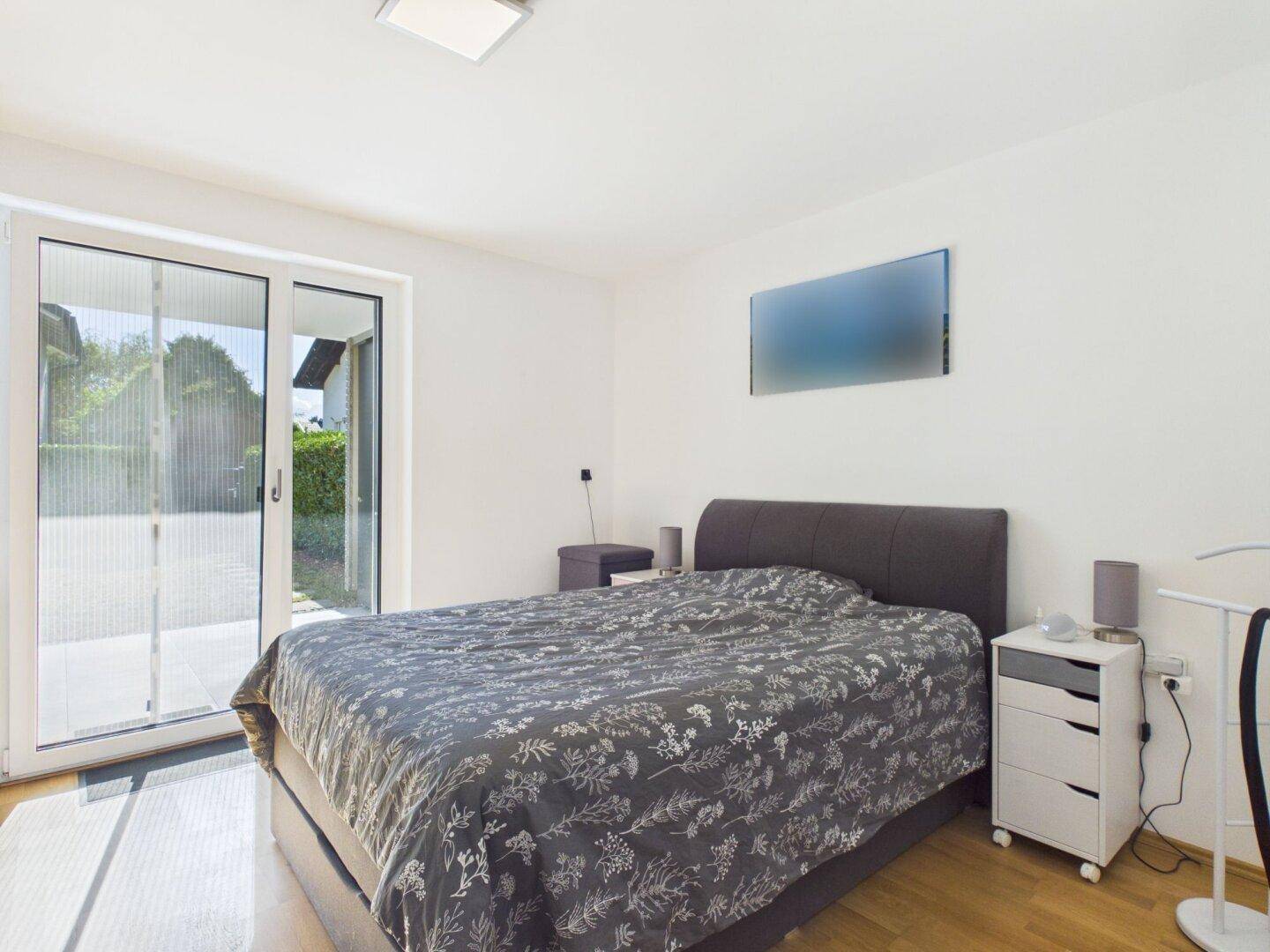 Helles Schlafzimmer mit Holzboden und direktem Zugang zu einem Außenbereich.