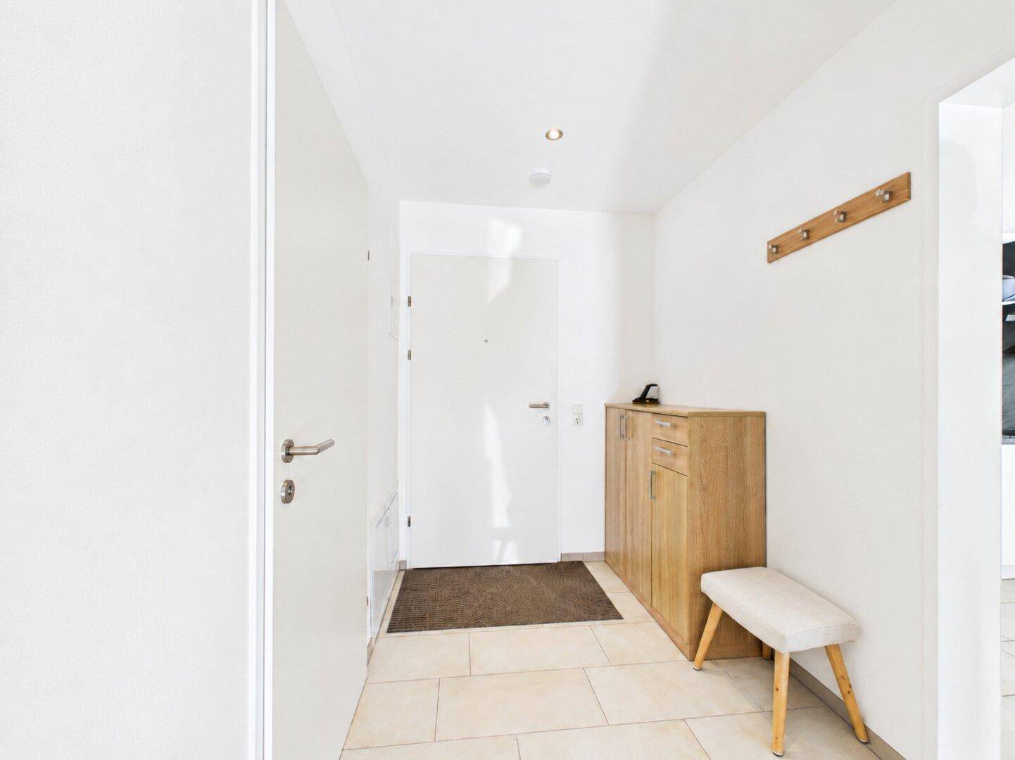 Heller Eingangsbereich mit Fliesenboden, Garderobe und Schuhschrank.