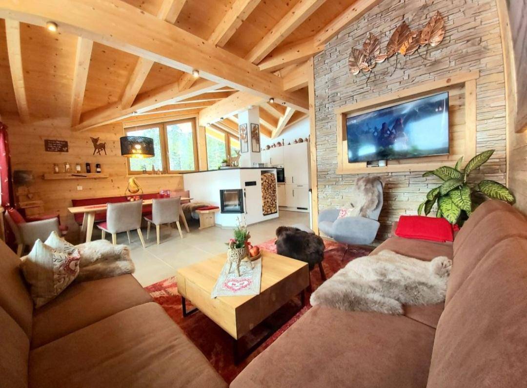 Gemütlicher Wohn-Essbereich mit Holzbalken, Kamin und rustikaler Steinwand.