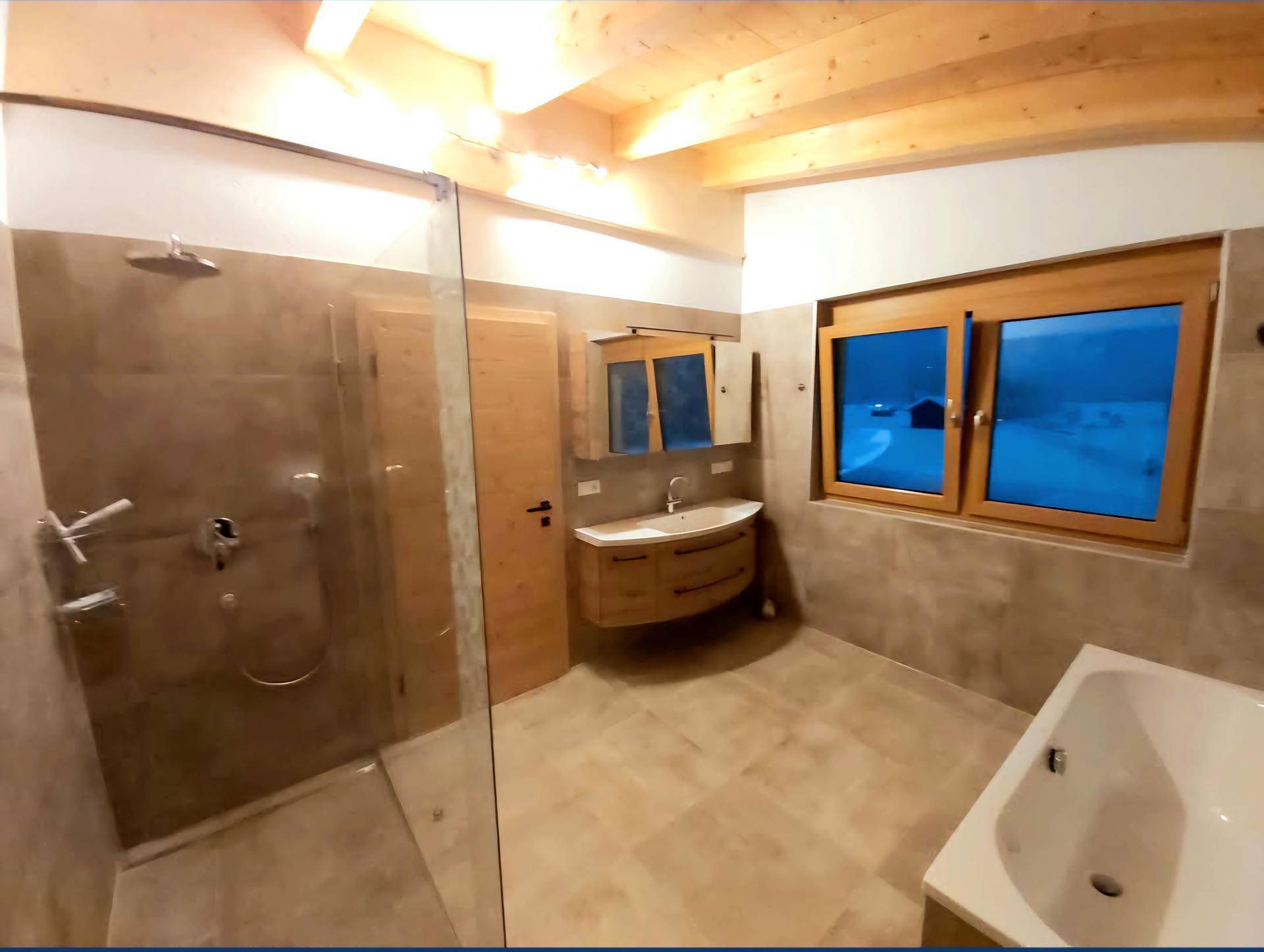 Geräumiges Badezimmer mit begehbarer Dusche, Badewanne, Holzwaschtisch und Fenster.