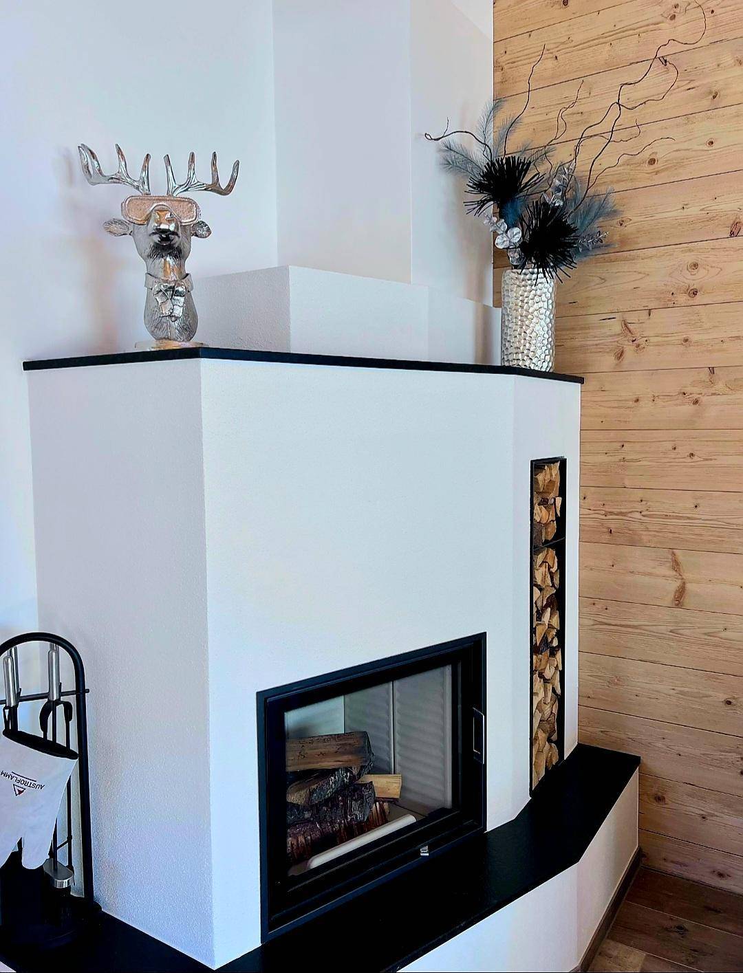 Moderner Kamin mit integriertem Holzfach und Hirschkopf-Dekoration in einem Wohnbereich.