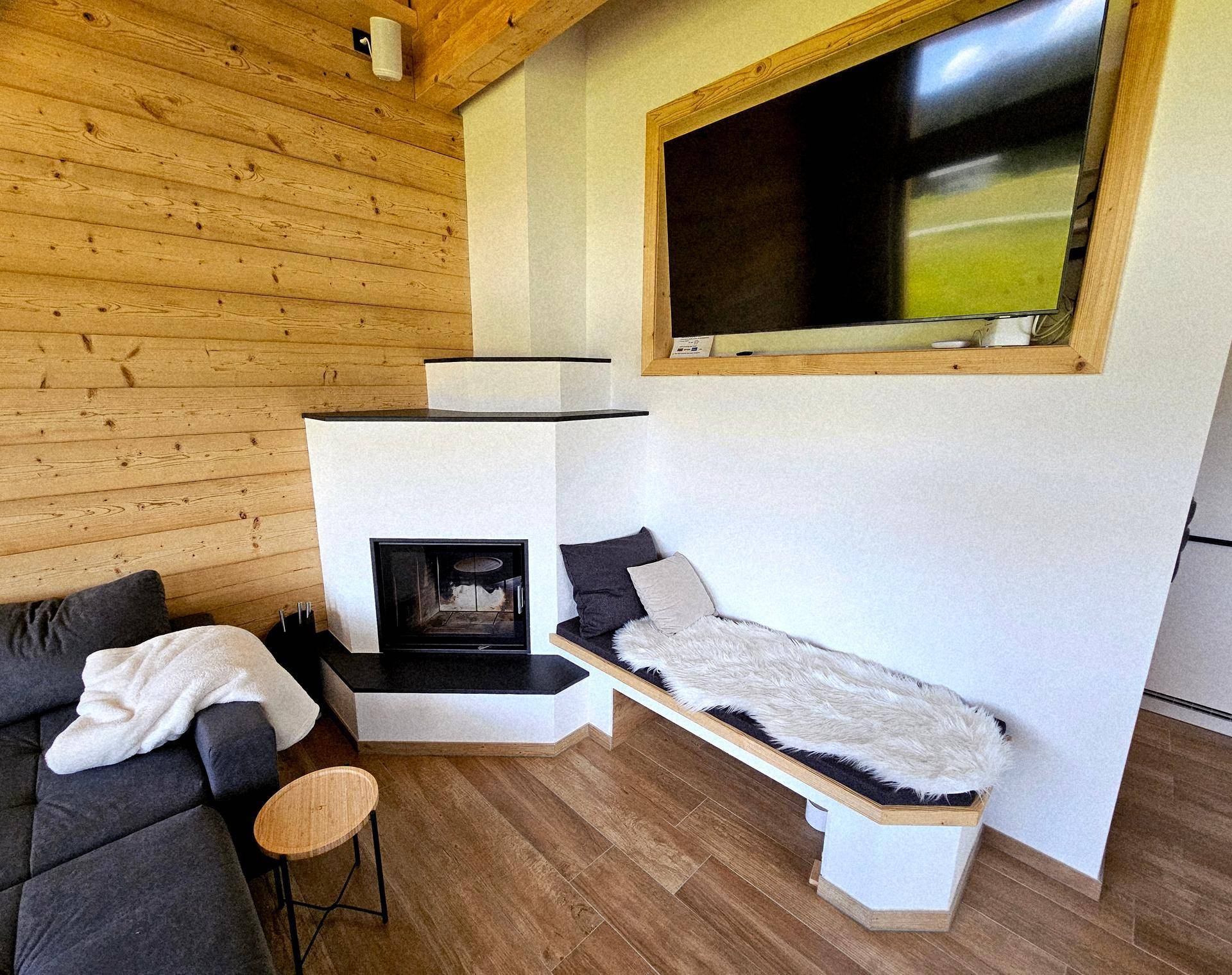 Gemütliches Wohnzimmer mit Eckkamin, Holzwandverkleidung und einer integrierten Sitzbank.
