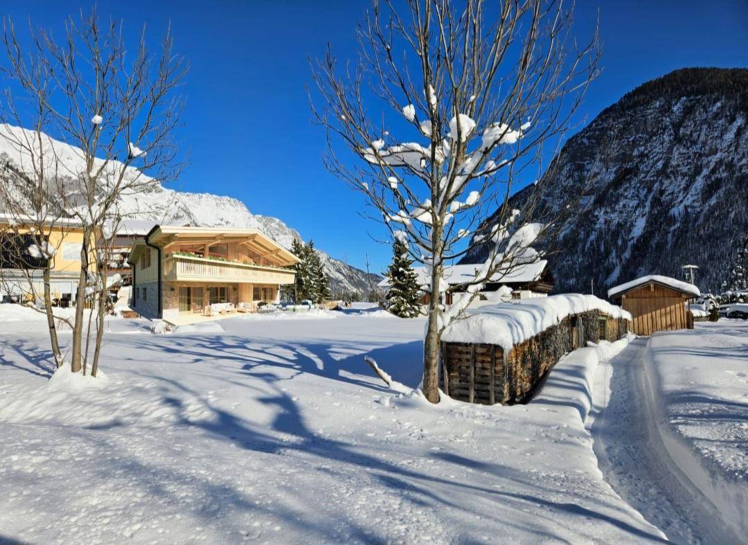 Traditionelles Holzhaus in einer idyllischen, schneebedeckten Winterlandschaft mit Bergen.