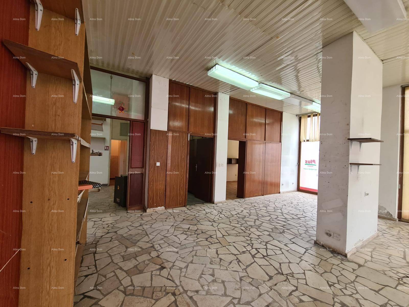 Großer Geschäftsraum mit Mosaikboden, Holzverkleidungen und Regalen an der Seite, gut beleuchtet.