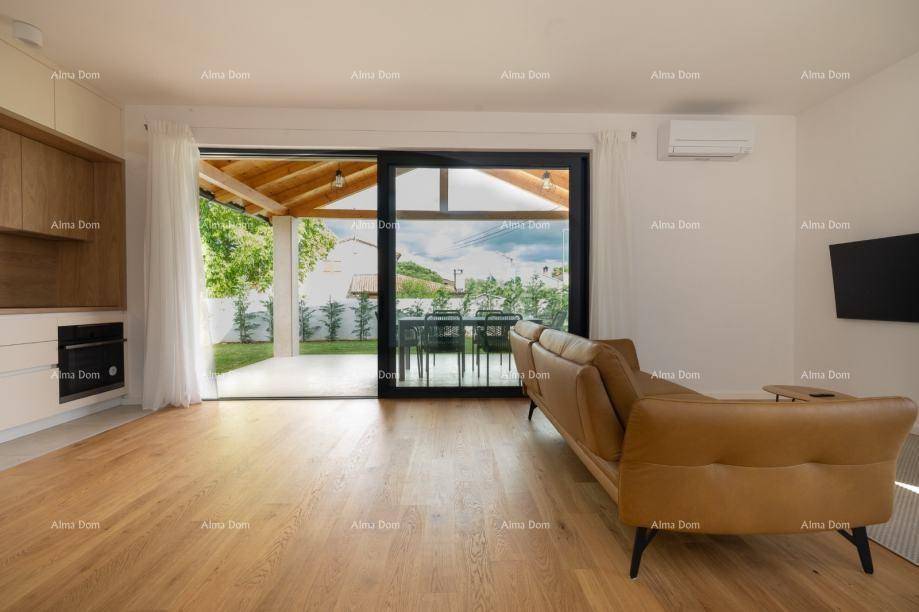 Gemütliches Wohnzimmer mit Holzboden, Ledersofa und großem Schiebefenster zum Garten.