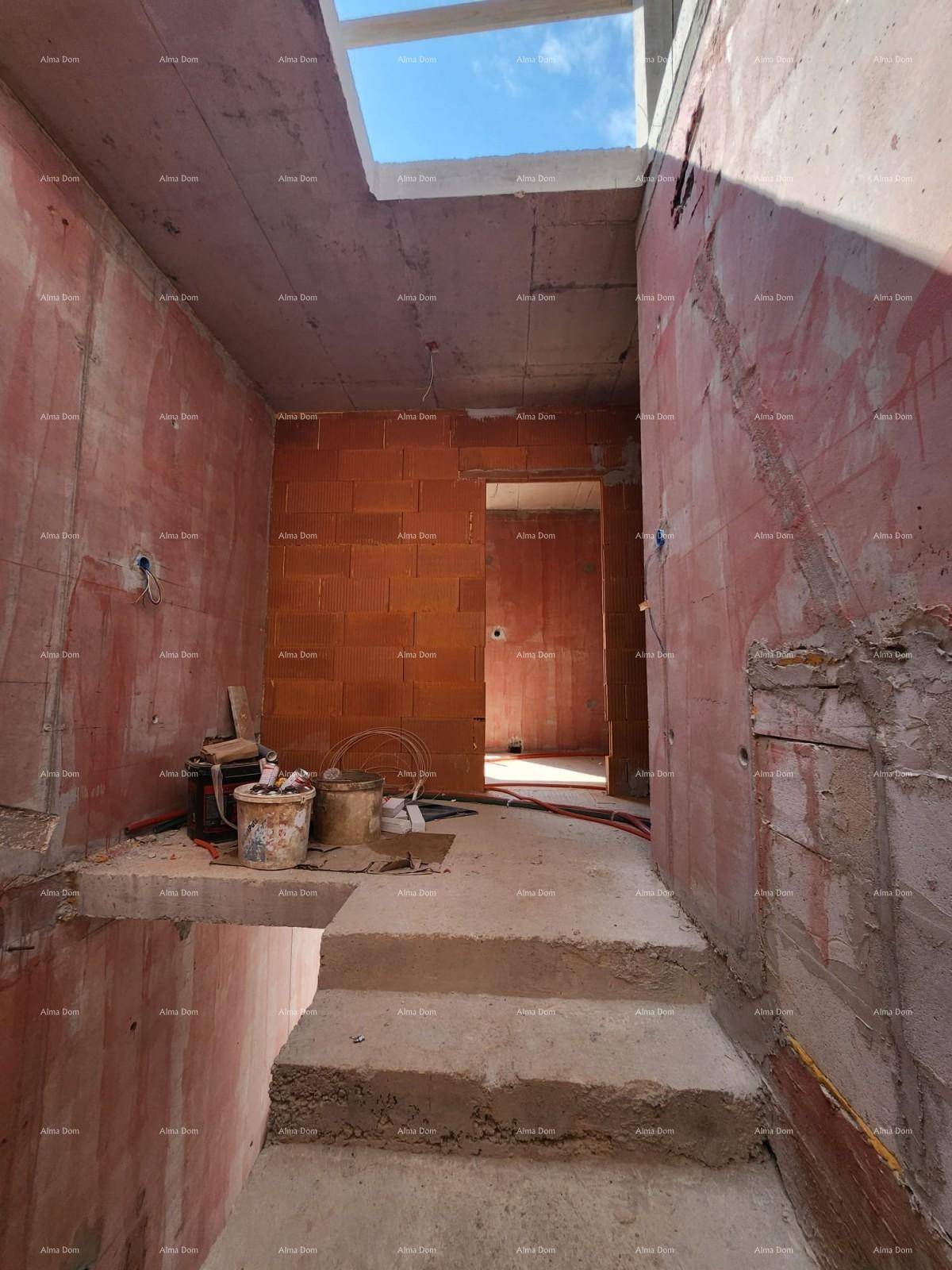 Treppenhaus im Rohbau mit Betonstufen, unverputzten Wänden und einem Oberlicht für Tageslicht.