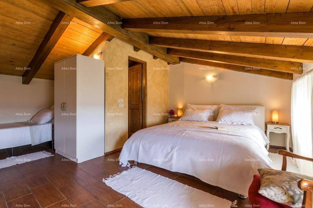 Gemütliches Schlafzimmer im Dachgeschoss mit Holzbalken, Holzboden und weißem Kleiderschrank.