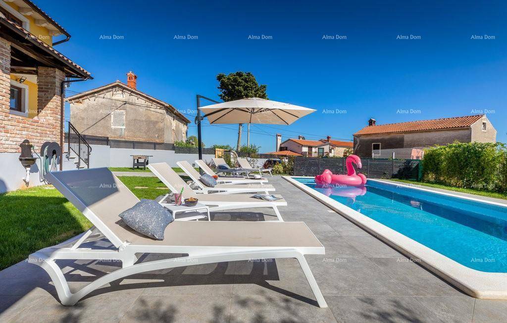 Entspannungsbereich am Pool mit bequemen Sonnenliegen und einem großen Sonnenschirm unter blauem Himmel.