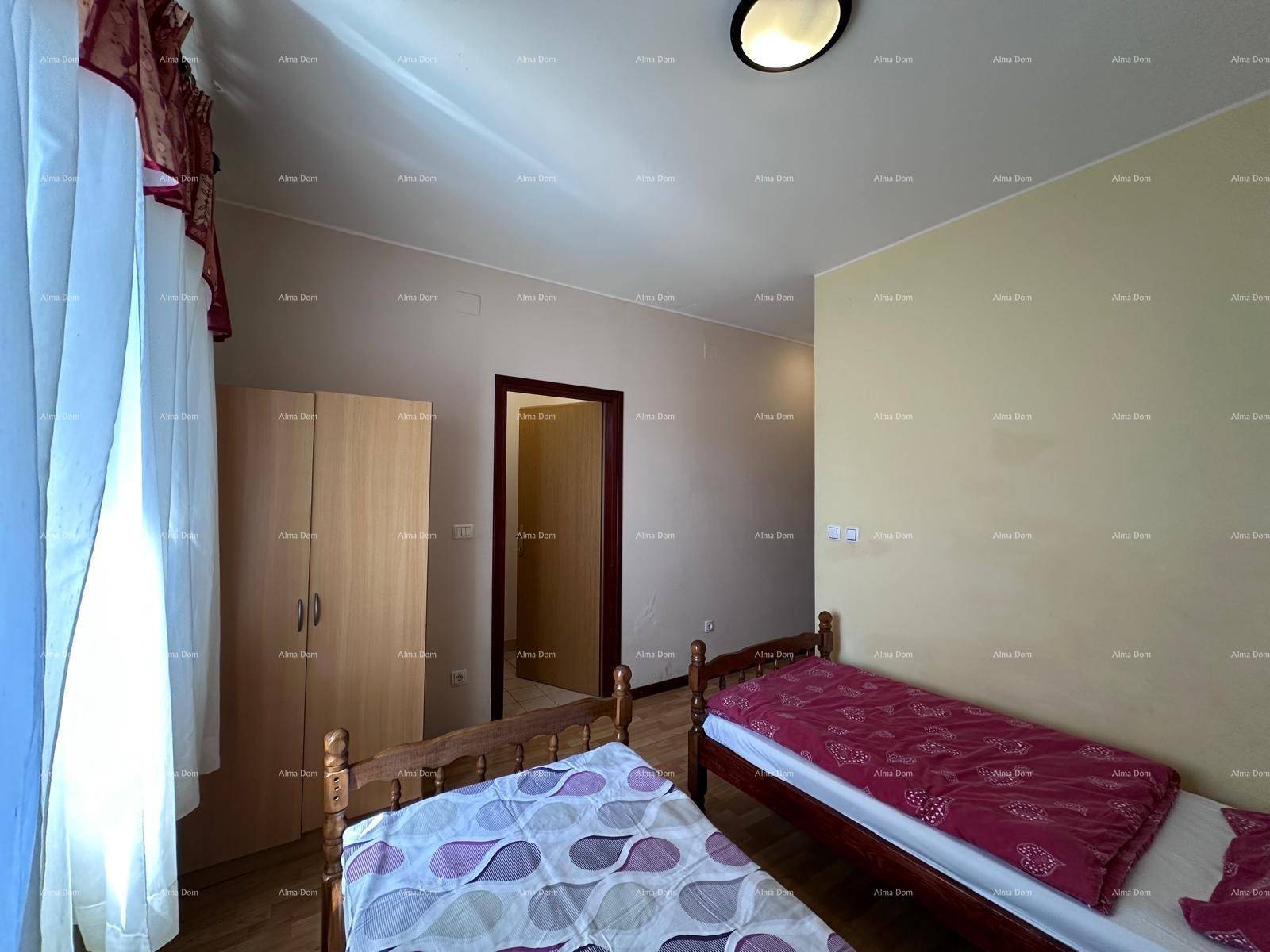 Geräumiges Schlafzimmer mit zwei Einzelbetten und Holzschrank, mit Zugang zu einem weiteren Raum.