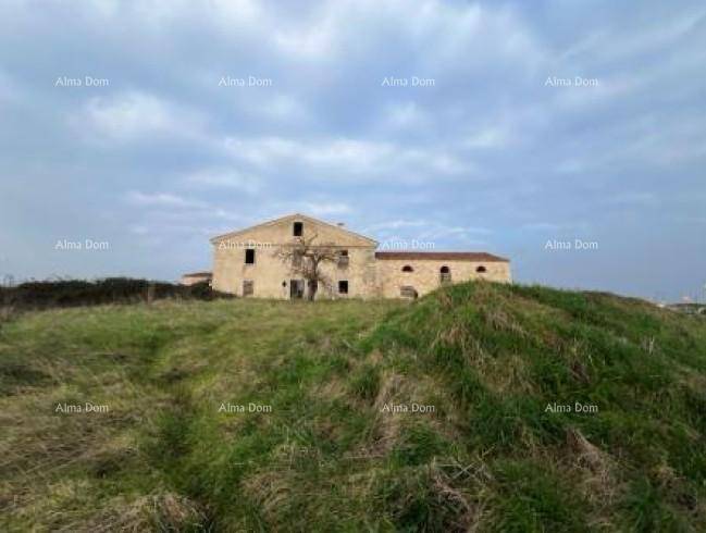 Historisches Steinhaus auf einem grasbewachsenen Hügel unter bewölktem Himmel, umgeben von Natur.