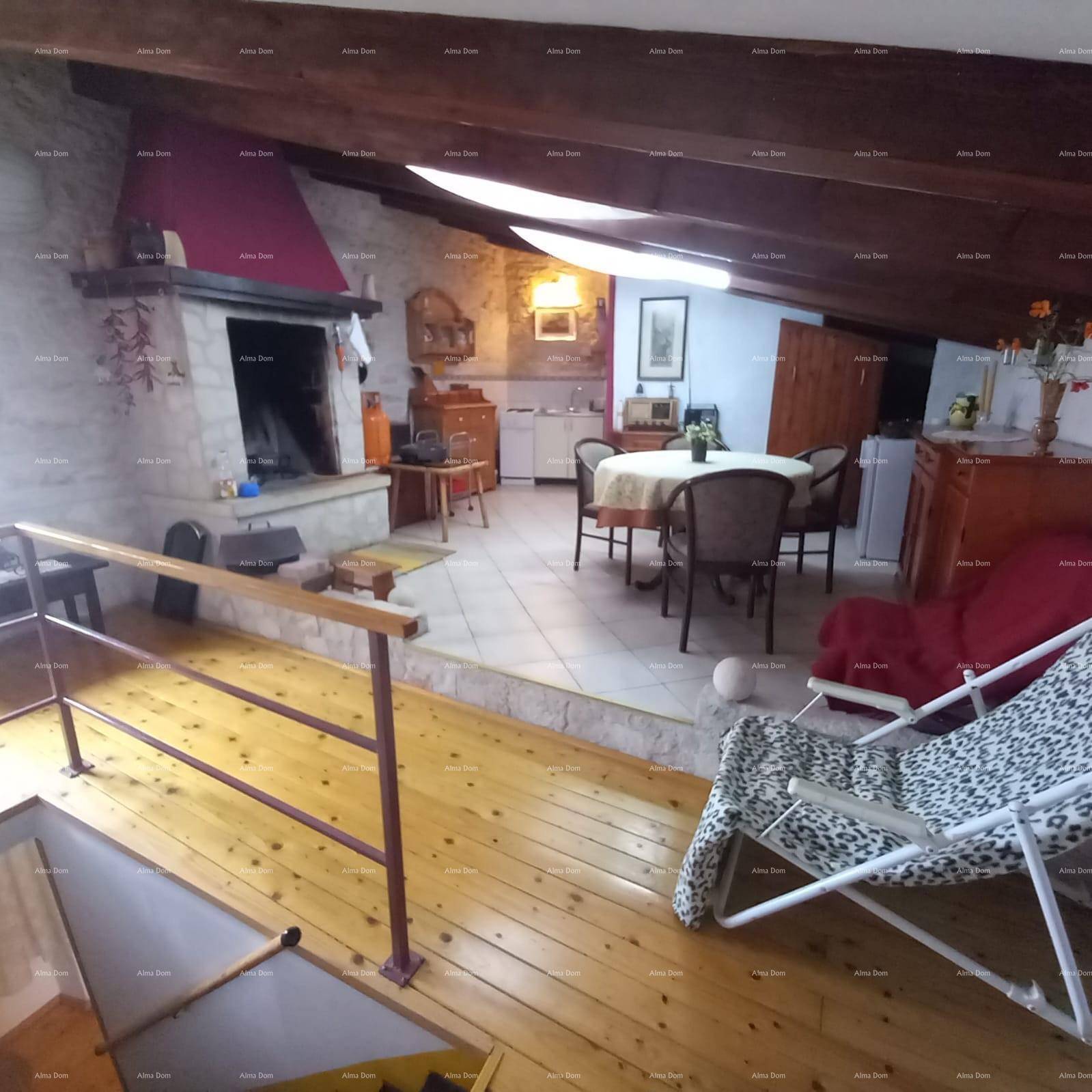 Geräumiger Wohn- und Essbereich im Dachgeschoss mit Kamin, Holzbalken und Fliesenboden.