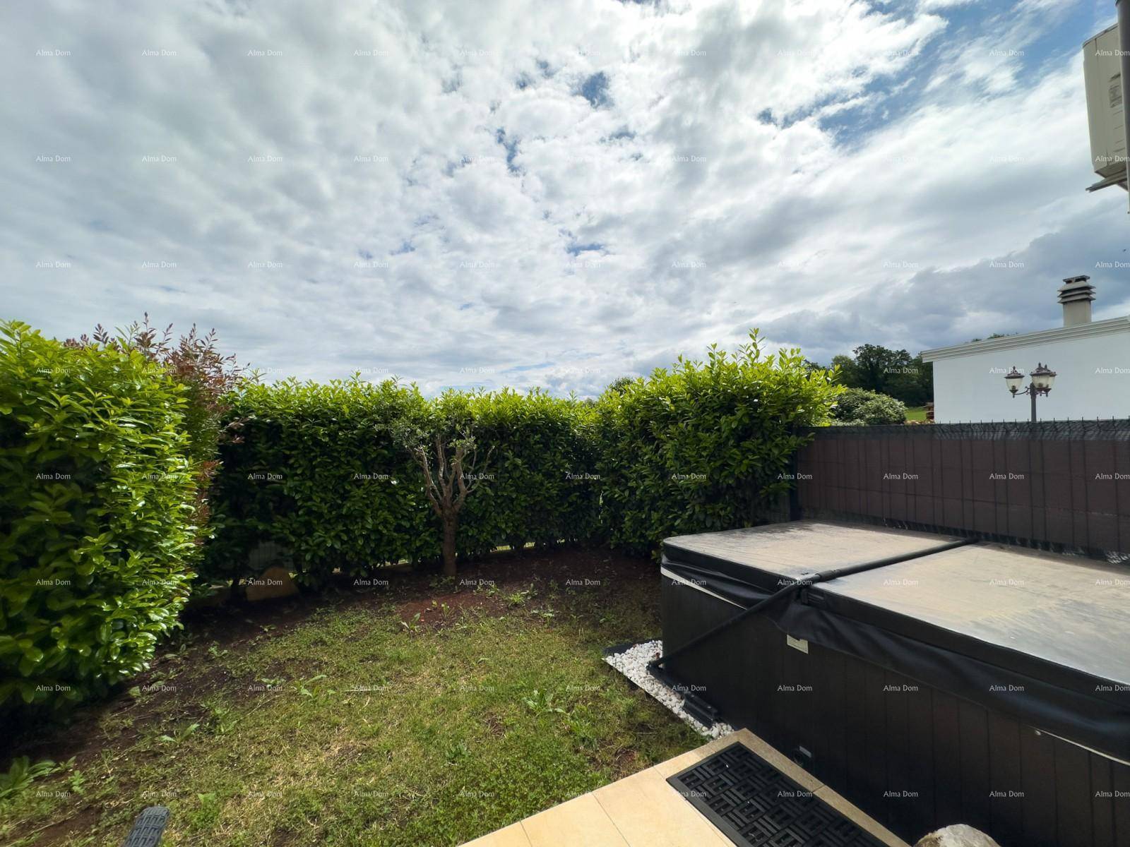 Gartenbereich mit gepflegter Hecke, Rasen und einem Whirlpool unter bewölktem Himmel.